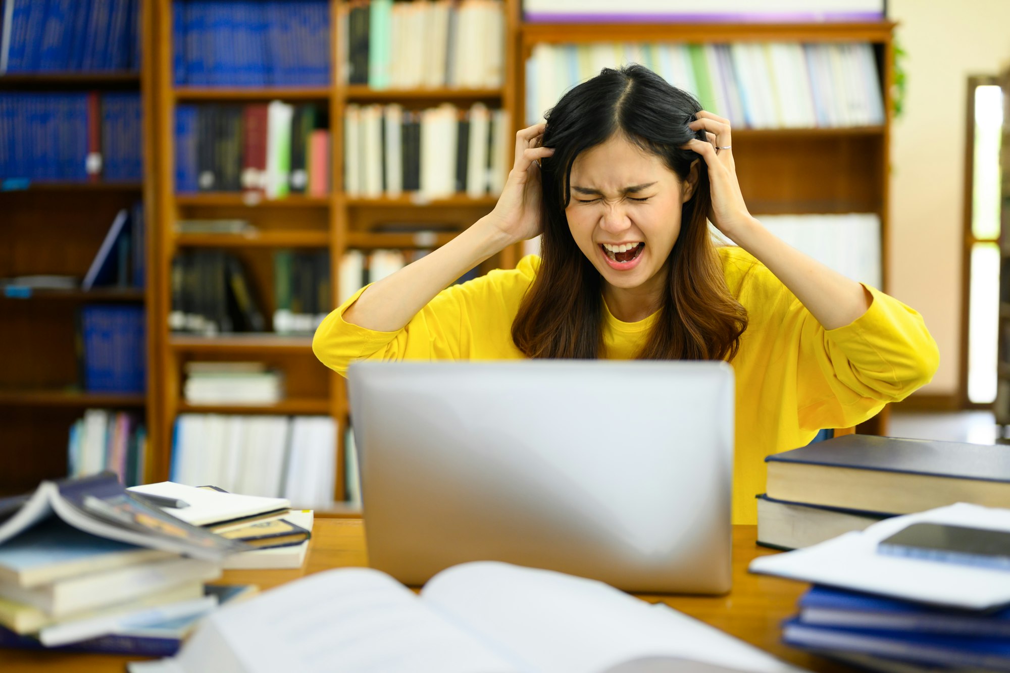 Stressed female college student feeling tired of studying for college exam.