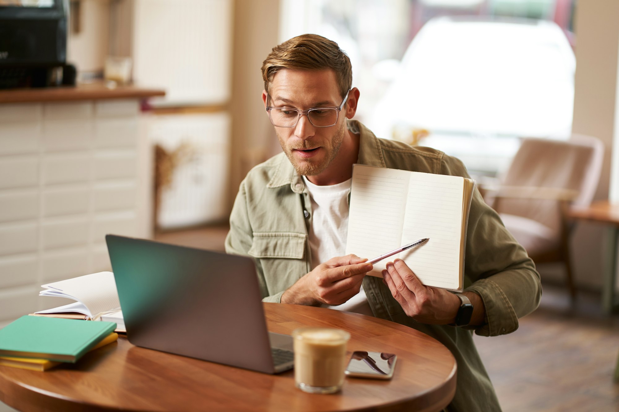 Portrait of young handsome man in glasses, private tutor teaching student online, pointing at his
